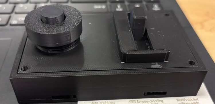 Black printed wrist-control housing with rotary cap and switch feature on a laptop.